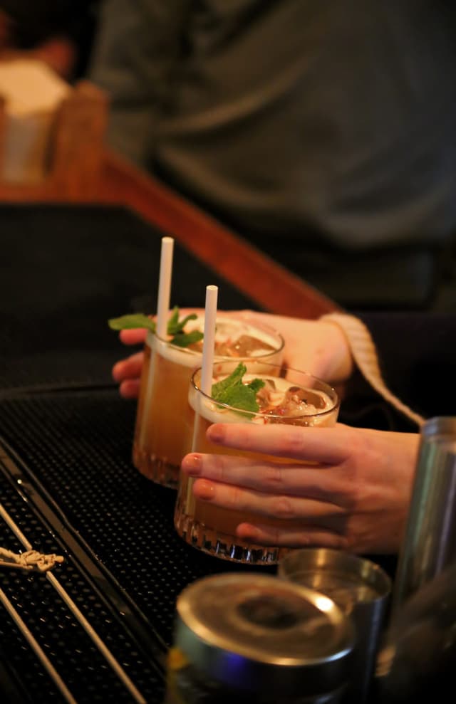 A person collecting their cocktails form the bar
